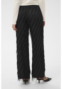 Czarne spodnie o szerokich nogawkach z teksturowanym detalem frędzli i ukośnymi paskami. Gładka tkanina z kontrastującym elementem zdobniczym na nogawkach.
