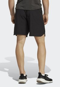 Pantalones cortos negros con bolsillos laterales, hechos de tela ligera. Presentan una textura sutil y aberturas laterales para facilitar el movimiento.
