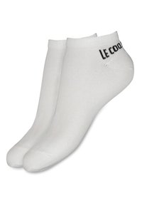 Calcetines tobilleros blancos hechos de una mezcla de algodón, con una textura suave y puños acanalados, y el logo "Le Coq Sportif" en negro.