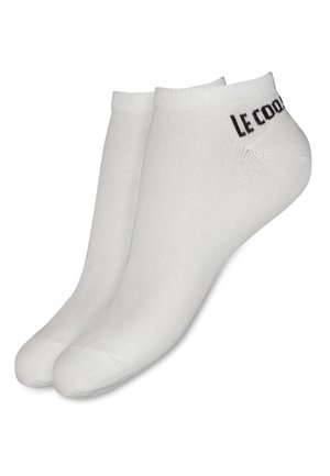 Calcetines tobilleros blancos hechos de una mezcla de algodón, con una textura suave y puños acanalados, y el logo "Le Coq Sportif" en negro.