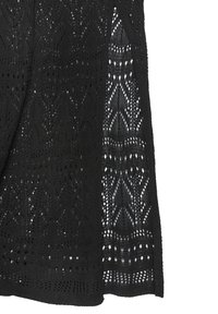 Schwarzer Strickstoff mit komplizierten geometrischen und floralen Durchbruchmustern sowie gezackten Kanten.
