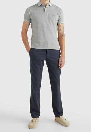 Gray polo shirt with collar, paired with dark patterned pants and light beige slip-on shoes. The outfit features a casual design and fit.