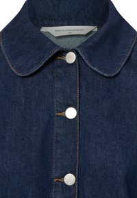 Ciemnoniebieska koszula dżinsowa z kołnierzykiem, srebrnymi zatrzaskami i kontrastującym przeszyciem wzdłuż szwów. Widoczna metka MSCH Copenhagen.