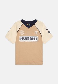 Beżowo-brązowa sportowa koszulka z krótkim rękawem, granatowym kołnierzem, logo i napisem "HUMMEL" na przodzie.