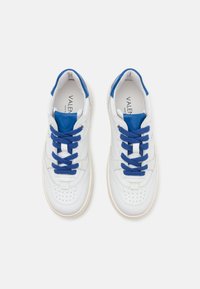 Baskets en cuir blanc avec des accents bleus et de grosses lacets bleus. Présentent des perforations au niveau des orteils et un panneau latéral texturé.