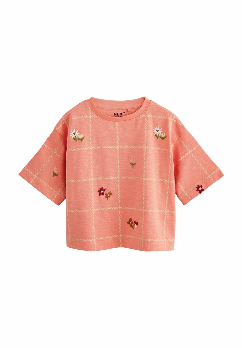 Korallfärgad T-shirt med kort ärm som har broderade blommönster och ett rutmönster med kontrasterande sömmar.