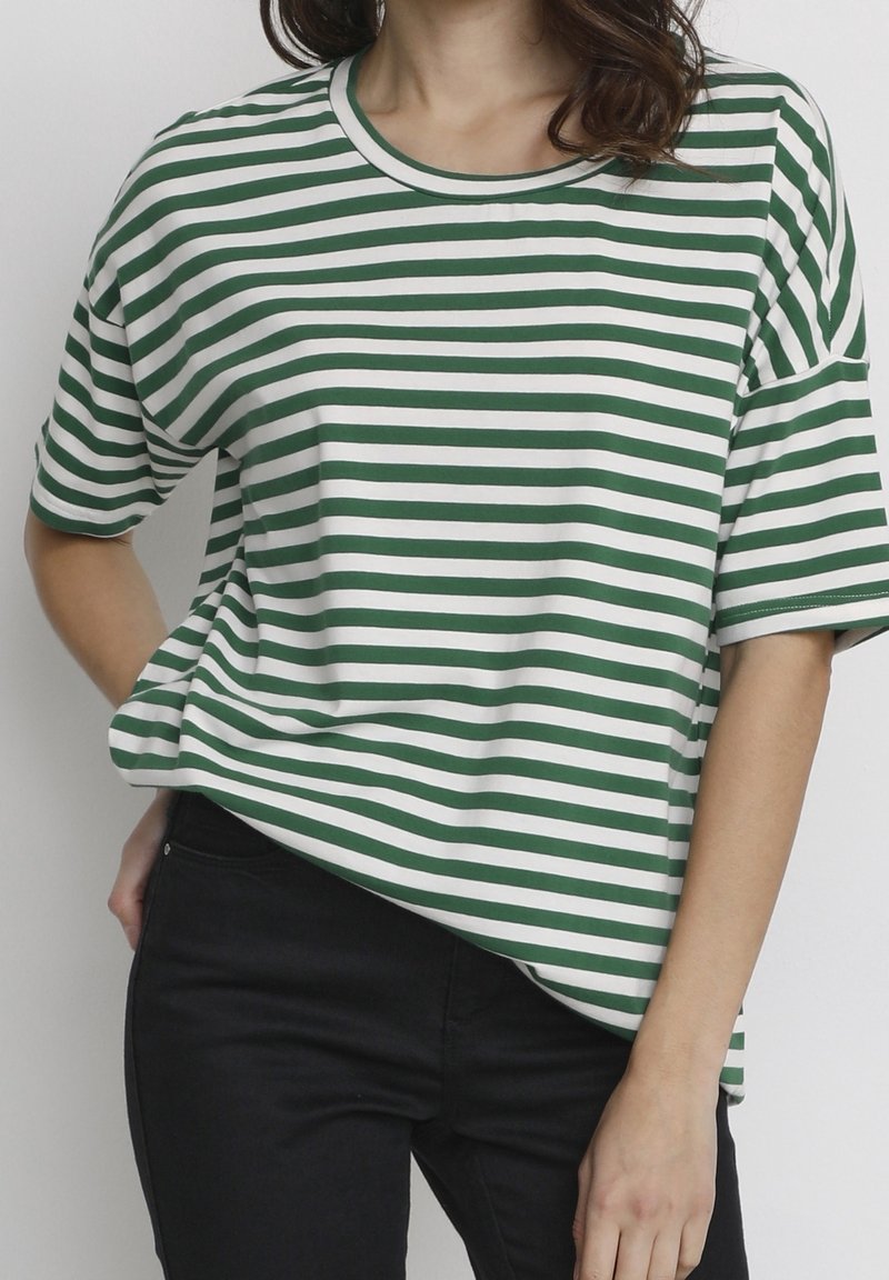 Camiseta a rayas verdes y blancas, de mangas cortas, con cuello redondo, corte relajado, tela suave, combinada con jeans negros.