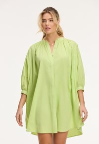 Abito camicia verde chiaro con maniche a palloncino e scollo arr gathered, caratterizzato da una vestibilità comoda e un orlo curvo.