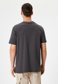 Camiseta de manga corta para hombre en gris oscuro, hecha de una tela suave, con cuello redondo y corte recto, con detalles de costura mínimos.