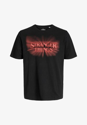 Must värvi puuvillane T-särk, millel on punane "STRANGER THINGS" logo plahvatusefektiga. Ümmargune kaelus, lühikesed varrukad ja mugav lõige.