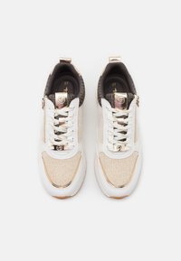 Sneakers with a cream and beige mesh upper, white leather accents, gold hardware, and textured dark brown details; includes laces and zip closure.