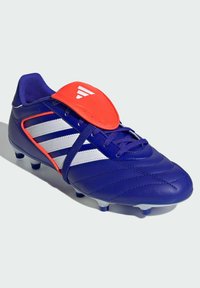 Botín de fútbol azul con parte superior de cuero texturizado, cubierta de cordones naranja y tres franjas blancas. Cuenta con tacos moldeados para una mejor tracción.