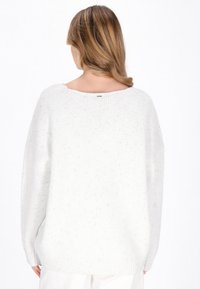 Maglione bianco lavorato a maglia con una vestibilità rilassata, scollatura ampia e texture visibile. Presenta venature grigie, con polsini e orlo a coste.