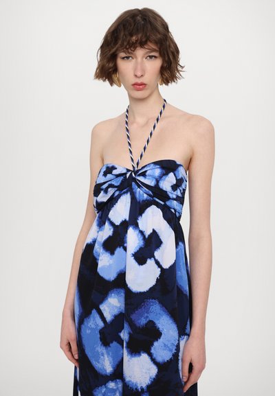 Robe halter à motif bleu avec un détail de nœud torsadé au niveau de la poitrine. Fabriquée en tissu léger avec différentes nuances de bleu et de blanc.