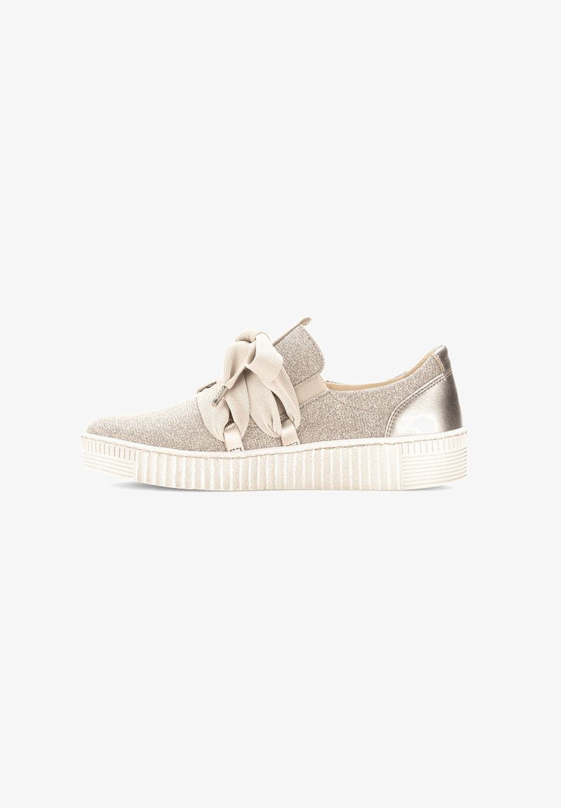 Beige sneaker with a textured fabric upper, featuring a large bow and metallic heel accent, set on a white, ridged rubber sole.