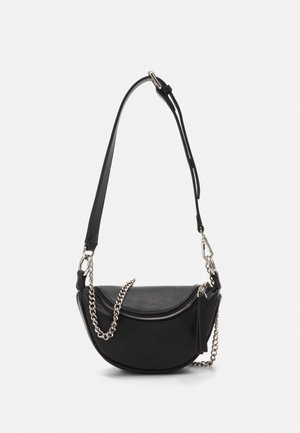Sac bandoulière noir en forme de demi-lune avec sangle réglable, fermeture éclair argentée et détail de chaîne argentée décorative sur fond uni.
