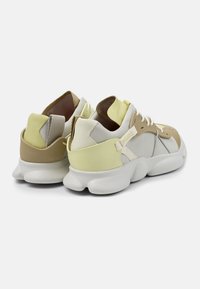 Lime green and beige sneakers feature a textured upper with varying leather and mesh panels, and a chunky white sole with distinct curves.