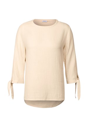 Beige, långärmad blus med rund halsringning, knutna ärmdetaljer och en något rundad nederkant. Tillverkad av ett lätt, texturerat tyg.