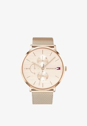 Montre-bracelet analogique ton or avec bracelet en maille, cadran minimaliste, deux sous-cadrans et logo Tommy Hilfiger avec drapeau rouge, blanc et bleu.