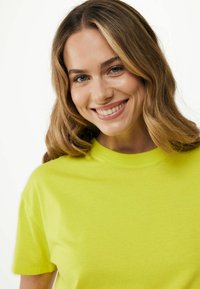 Krátký rukáv tričko světle limetkové barvy z bavlněné tkaniny s kulatým výstřihem a hladkou texturou, s volným střihem.