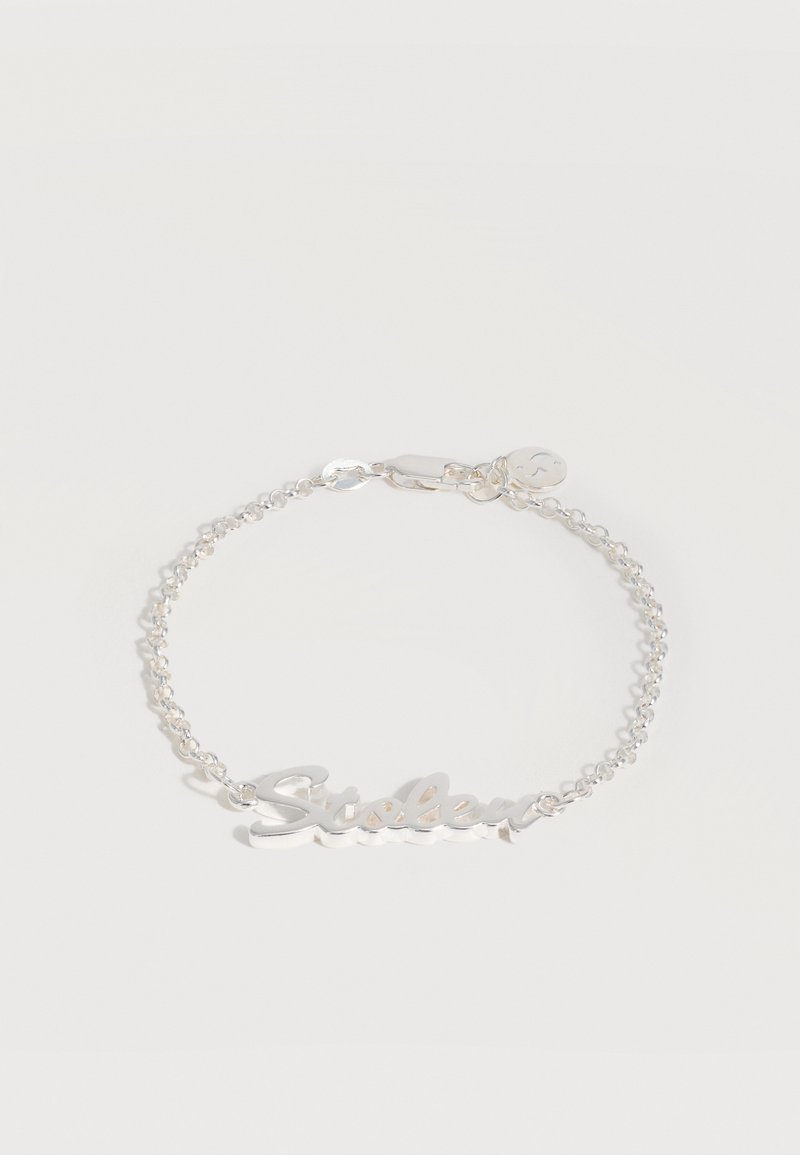 Ασημένιο βραχιόλι με αλυσίδα και πλακέτα με καλλιγραφική επιγραφή "Sisley" και ένα μικρό στρογγυλό γούρι κοντά στο κούμπωμα σε λευκό φόντο.