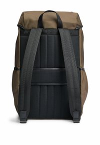 Ruskea reppu, jossa on musta pehmustettu takapaneeli, säädettävät mustat hihnat ja päällikahva valkoista taustaa vasten.