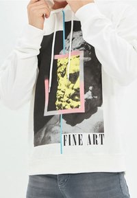 Felpa bianca con cappuccio, caratterizzata da una stampa grafica con accenti neri, rosa e gialli, che mostra una statua e il testo "FINE ART" nella parte inferiore.