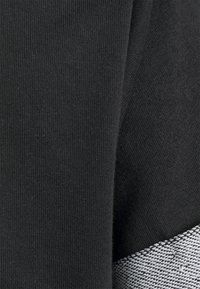 Czarna tkanina z teksturowanym wzorem, z kontrastującym szarym akcentem w skośną paskę. Gładka, dziana struktura ogólnie.