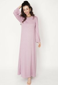 Długa, jasnoróżowa sukienka prążkowana z długimi rękawami i rozcięciami po bokach, wykonana z miękkiego, teksturowanego materiału, charakteryzująca się luźnym krojem.