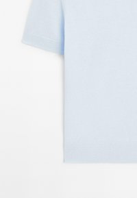 Maglione azzurro chiaro a maniche corte realizzato in un tessuto morbido, con dettagli dell'orlo e delle maniche visibili su uno sfondo semplice.
