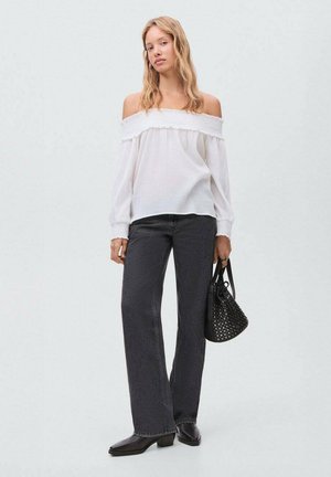 Hvid off-shoulder bluse med flæseudskæring, parret med højtaljede sorte jeans. Accessoriseret med en lille sort nittertaske.