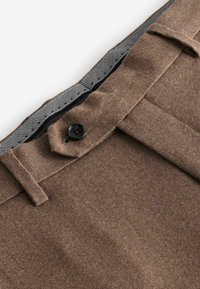 Pantalones de lana marrones con una textura suave, que cuentan con un cierre de botón negro y una cinturilla interior con estampado.