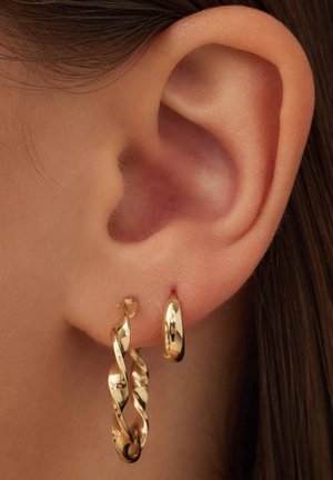 Boucles d'oreilles en or avec un design torsadé, suspendues à un petit anneau, surface polie pour brillance et textures lisses.