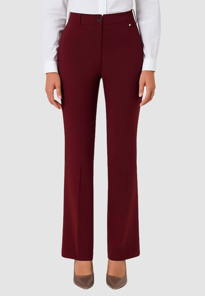 Pantaloni color mogano con taglio su misura, fronte piatto e leggero svasamento sul fondo. Presentano una chiusura con bottone e dettagli discreti sulle tasche.