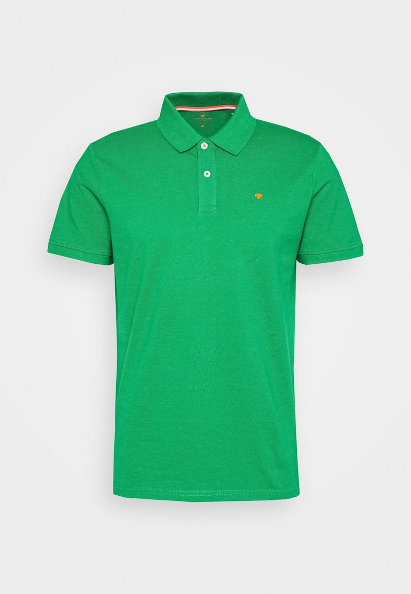 Polo en coton vert avec une patte de boutonnage à deux boutons, des manches courtes, et un petit logo orange sur la poitrine. Texture lisse.