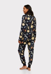 Ensemble de pyjama navy avec un motif de soleil et de lune en crème, orange et or. Tissu doux avec des manches longues et des poignets élastiques sur le pantalon.