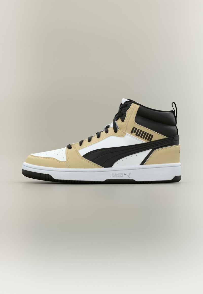 Høyhøye Puma-sneakers i beige, svart og hvitt med svarte lisser og logo på siden og sålen, plassert mot en enkel lys bakgrunn.