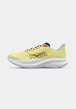 HOKA hardloopschoen in felgeel met zwarte veters, een gestructureerde bovenkant en lichtblauwe accenten. Dikke witte tussenzool met een gebogen vorm.