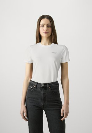 Hvid bomulds t-shirt med rund halsudskæring og korte ærmer, med et lille logo i sort. Båret med højtaljede mørke denim jeans.