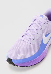 Μωβ αθλητικό παπούτσι με άνω μέρος από δίχτυ, λευκή κωδ-επιγραφή και καουτσούκ σόλα. Διαθέτει κυμ ατιστά σχέδια και επίπεδα κορδόνια για ασφαλή εφαρμογή.