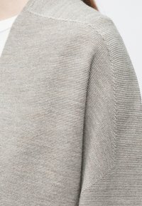 Cardigan in maglia grigio chiaro con finitura testurizzata, caratterizzato da una vestibilità comoda e apertura frontale senza bottoni visibili o fantasie.
