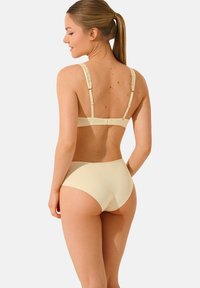 Ensemble de lingerie beige comprenant un soutien-gorge simple avec des bretelles bordées de dentelle et un bas taille haute assorti, fabriqué à partir d'un tissu lisse et extensible.