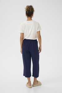 Pantalons cropped légers navy avec une taille élastique, associés à un t-shirt en coton blanc ample et des sandales à glissière beiges.