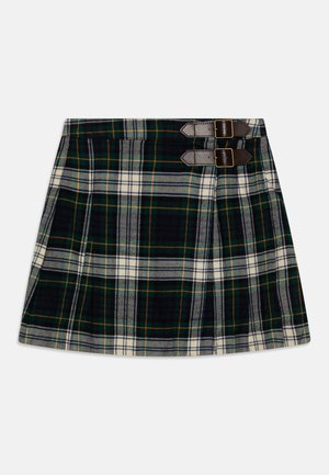 Jupe plissée tartan longueur genou en vert foncé, bleu marine et blanc avec deux brides marron à boucle à la taille.