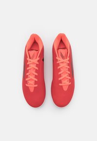 Røde atletiske sko med struktureret overdel, tynde sorte sideakcenter og ferskenfarvede snørebånd. Har et strømlinet, sporty design og rund tå.
