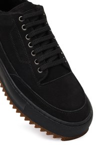 Baskets en suede noir avec lacets ronds, œillets en métal et semelle en caoutchouc texturé avec un bord en zigzag, présentant un design élégant.