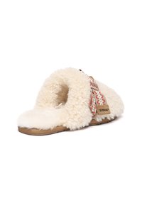 Sheepskin slipper with a beige sole. The upper is cream-colored fur with intricate red and white embroidery on a tan strap.