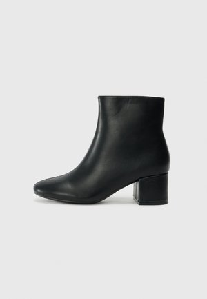 Black leather ankle boots with a pointed toe and a chunky heel. Smooth texture with minimal accents and a sleek, fitted design.