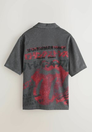 Tričko s krátkým rukávem v antracitově šedé barvě s červeným motivem jazyka Rolling Stones. Na zádech jsou různé nápisy a vzory. Vintage látka.