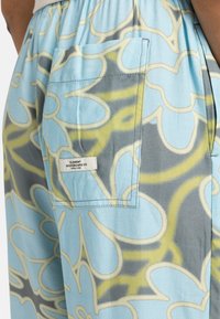 Pantalons bleu clair avec un motif floral en jaune et gris. Comprend une poche arrière avec une étiquette portant la mention "ELEMENT SKATEBOARD CO."